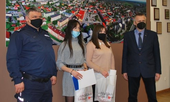 Zdjęcie na tle panoramy miasta Lubaczowa. od lewej Komendant Powiatowy Policji w Lubaczowie, dwie dziewczyny oraz Burmistrz miasta Lubaczowa