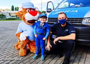 Policjant, Jaś i maskotka przed policyjnym radiowozem