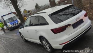 białe audi stojące obok radiowozu