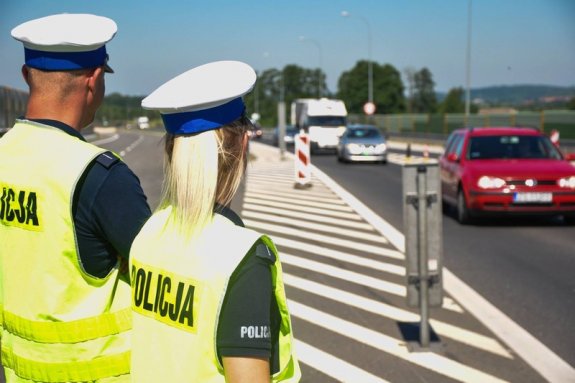 Funkcjonariusze ruchu drogowego stoją przy ulicy i wykonują czynności służbowe