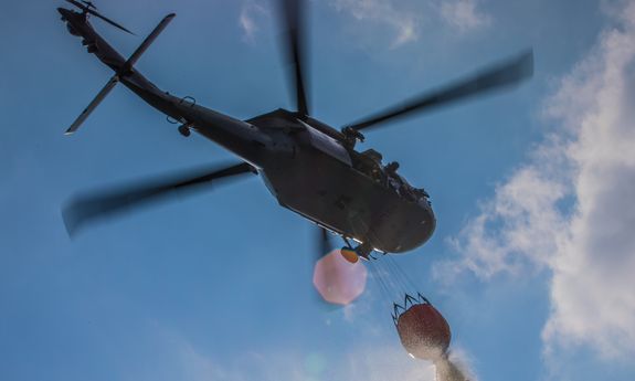 Policyjny śmigłowiec z podwieszonym pod nim zbiornikiem z wodą, tzw. Bambi Bucket - widok od dołu