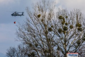 lecący policyjny śmigłowiec z podczepionym zbiornikiem z wodą, tzw. Bambi Bucket