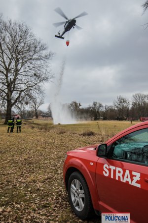 lecący policyjny śmigłowiec spuszcza wodę z tzw. Bambi Bucket