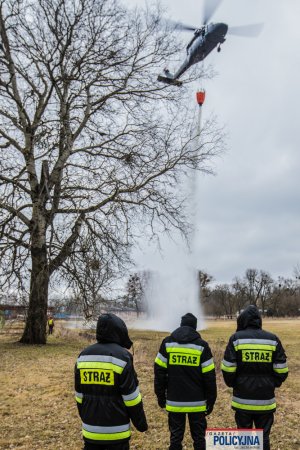 lecący policyjny śmigłowiec spuszcza wodę ze zbiornika, z tzw. Bambi Bucket