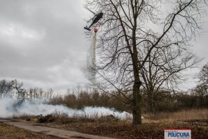 lecący policyjny śmigłowiec spuszcza wodę z podczepionego zbiornika z wodą, z tzw. Bambi Bucketu