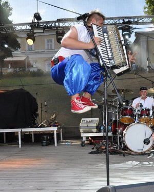 Zdjęcie przedstawia Piotrka Ostaszewskiego z akordeonem na scenie