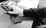 fragment ręki osoby sięgającej za słuchawkę telefonu - zdjęcie czarno-białe