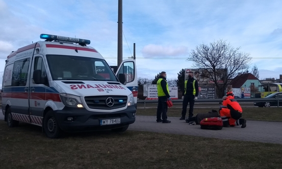 karetka pogotowia, obok ratownicy i policjanci podczas udzielania pomocy