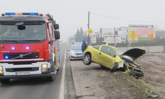 wóz strażacki obok rozbitego samochodu, w tle radiowóz policyjny