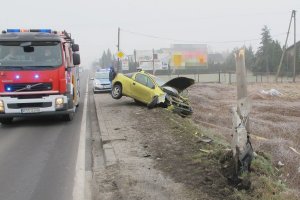 wóz strażacki obok rozbitego samochodu, w tle radiowóz policyjny