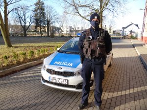 policjant stoi przed radiowozem policyjnym