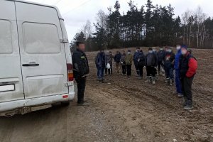 pasażerowie stoją obok busa na polu