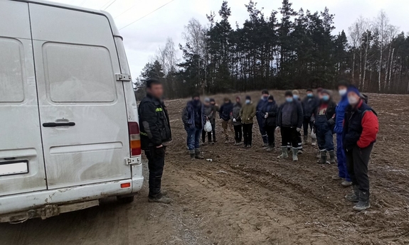 pasażerowie stoją obok busa na polu