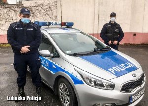 dwaj policjanci stoją przy radiowozie