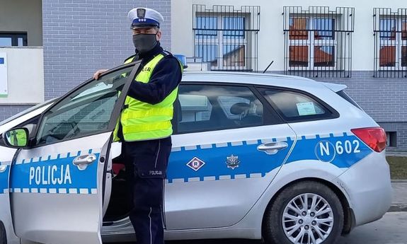 umundurowany policjant stoi przy radiowozie