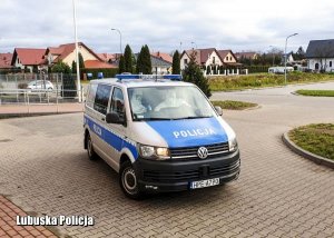 Radiowóz oznakowany, a w nim policjanci w kombinezonach
