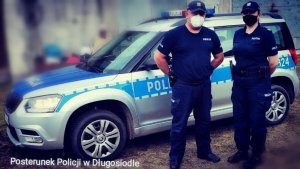 policjant i policjantka stoją przed radiowozem