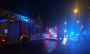 pojazdy służb ratunkowych z włączonymi sygnałami świetlnymi na miejscu pożaru budynku