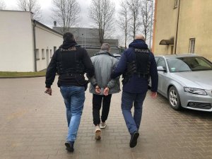 dwaj policjanci ubrani po cywilnemu prowadzą zatrzymanego