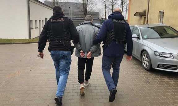 dwaj policjanci ubrani po cywilnemu prowadzą zatrzymanego