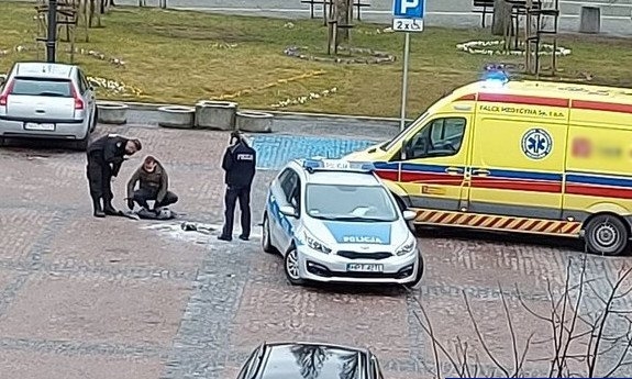 Miejsce zdarzenia. Stojący na placu policjanci obok radiowozu i karetki