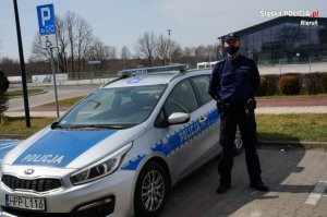 policjant stoi przy radiowozie