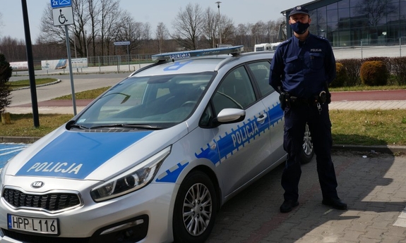 policjant stoi przy radiowozie