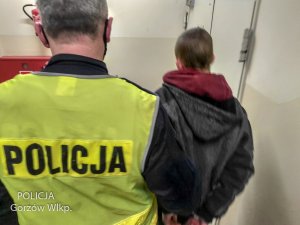 policjant w żółtej kamizelce z napisem Policja prowadzi zatrzymanego