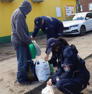 dwoje policjantów wręcza mężczyźnie przygotowane paczki