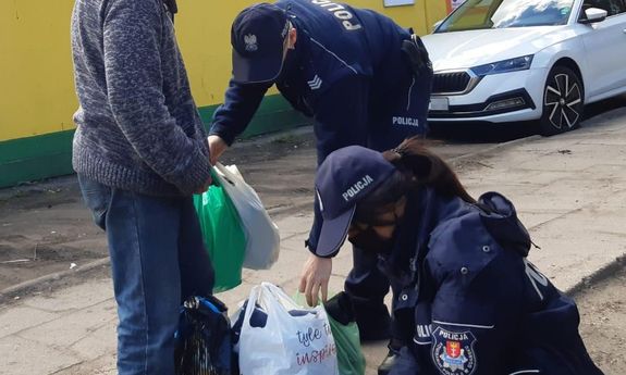 dwoje policjantów wręcza mężczyźnie przygotowane paczki