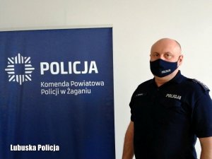 mężczyzna w koszulce z napisem policja, po lewej stronie baner z napisem Komenda Powiatowa Policji w Żaganiu