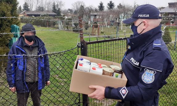 umundurowany policjant przekazuje mężczyźnie paczkę