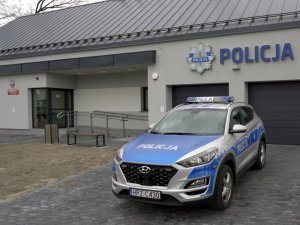 Oznakowany radiowóz stojący przed budynkiem Policji