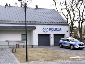 Oznakowany radiowóz stojący przed budynkiem Policji