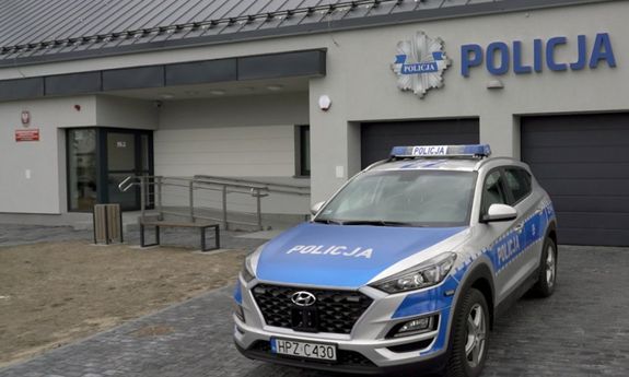 Oznakowany radiowóz stojący przed budynkiem Policji