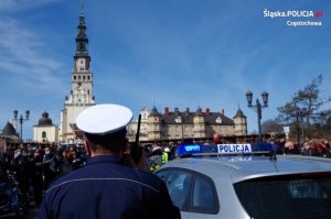 &quot;policjant w białej czapce na tle Jasnej Góry stoi przy radiowozie