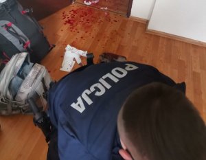 policjant udzielający pomocy mężczyźnie, który się sam okaleczył