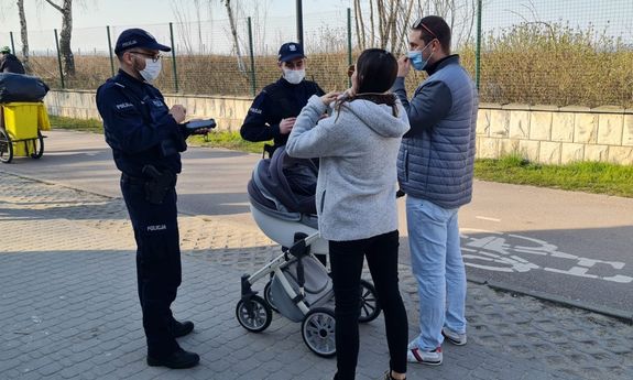 Stróże prawa zwracają uwagę kobiecie i mężczyźnie z wózkiem na zakrywanie ust i nosa maseczką