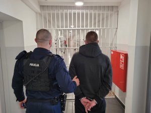 Policjant prowadzi zatrzymanego mężczyznę