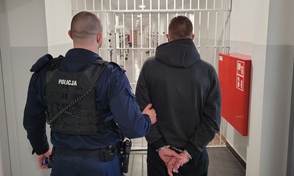 Policjant prowadzi zatrzymanego mężczyznę