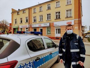 policjant stoi obok radiowozu policyjnego