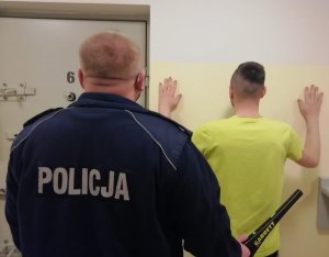 zatrzymany mężczyzna i policjant - widok z tyłu