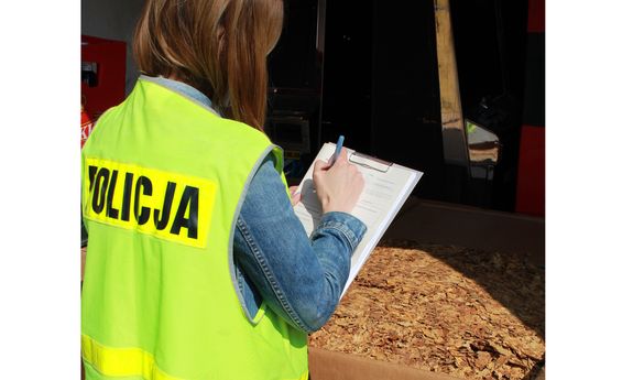 policjantka w kamizelce odblaskowej spisuje protokół stojąc przy pudle z krajanką
