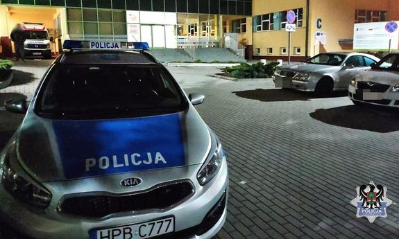 na zdjęciu widać radiowóz stojący przed szpitalem obok widać karetkę oraz inne pojazdy