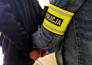 mężczyzna z opaska na ręku z napisem policja