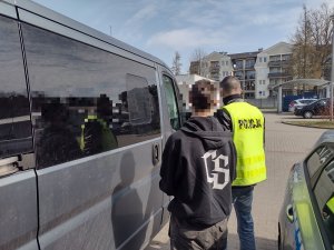 Zatrzymany mężczyzna prowadzony do nieoznakowanego samochodu przez policjanta