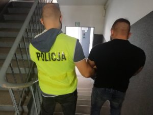 Policjant prowadzi zatrzymanego mężczyznę.&quot;&gt;