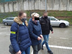 Zatrzymana kobieta prowadzona przez policjantów do radiowozu