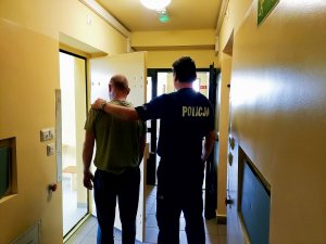 policjant prowadzi zatrzymanego mężczyznę&quot;&gt;