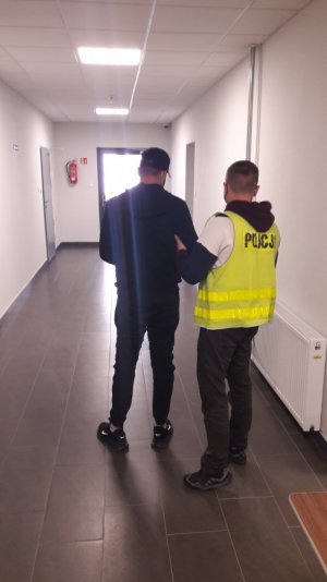 policjant prowadzi zatrzymanego mężczyznę